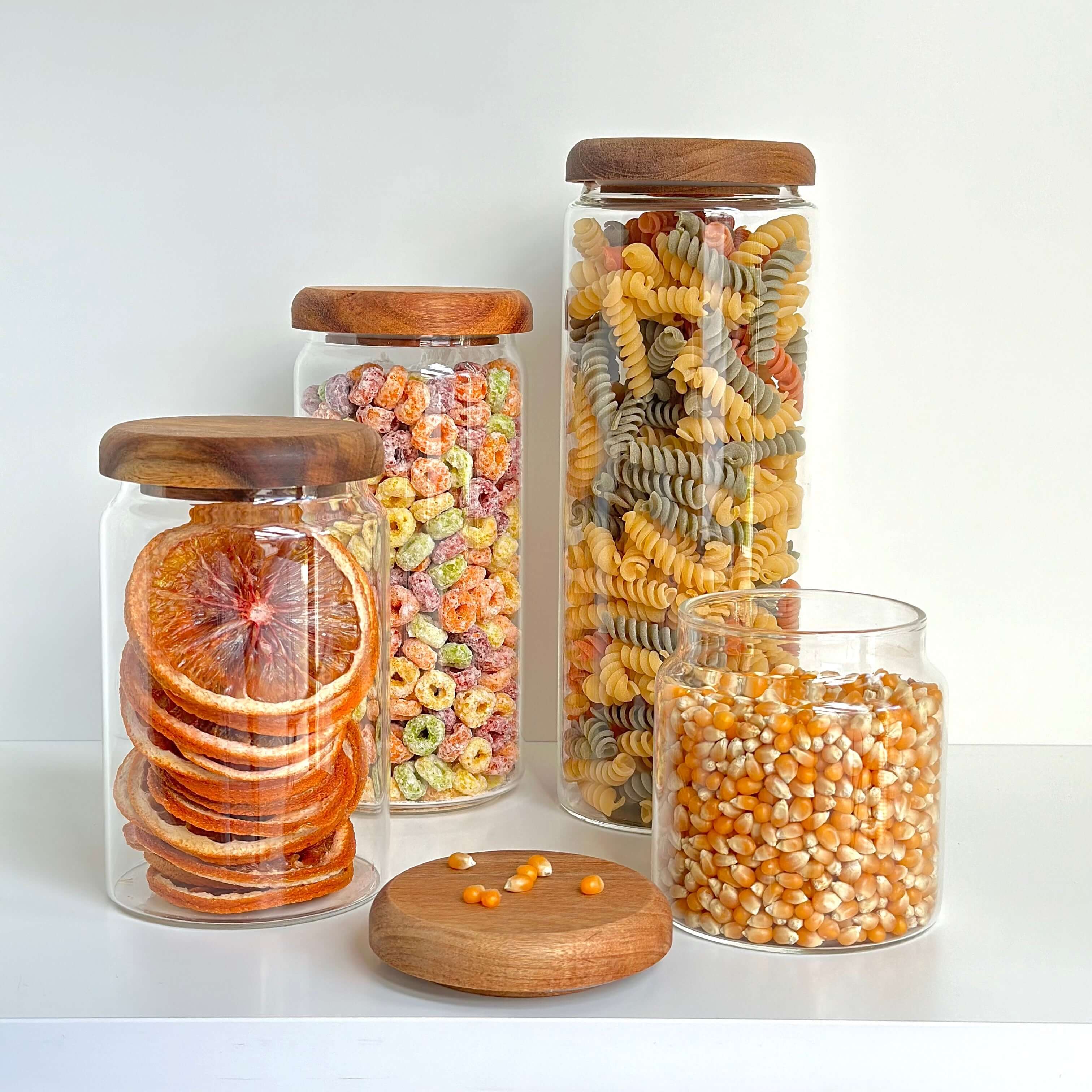 Set of glass jars with acacia lids filled with dried foods for pantry organization.