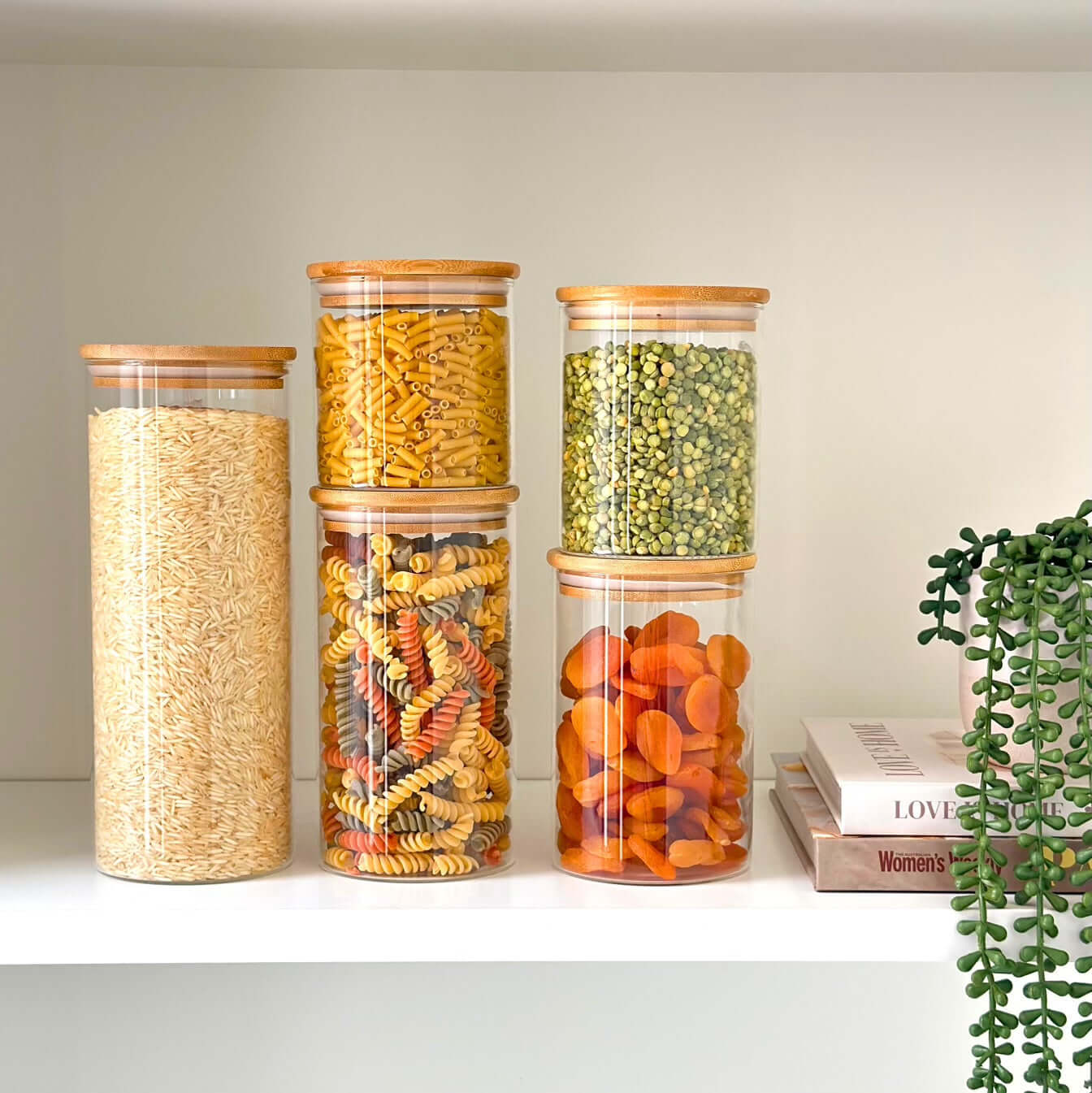 Organized pantry shelf with round glass storage jars and bamboo lids.