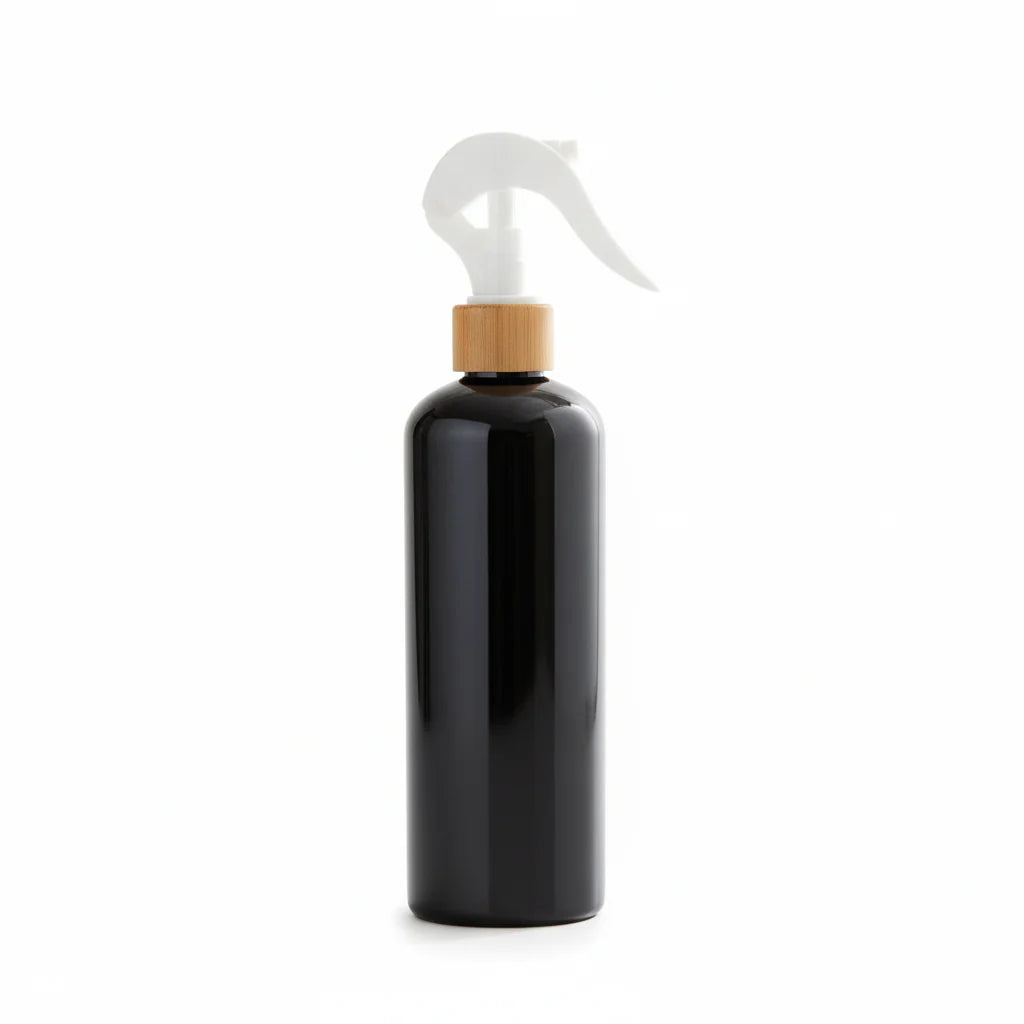 Black spray bottle with wooden cap on a light surface with plants in the background